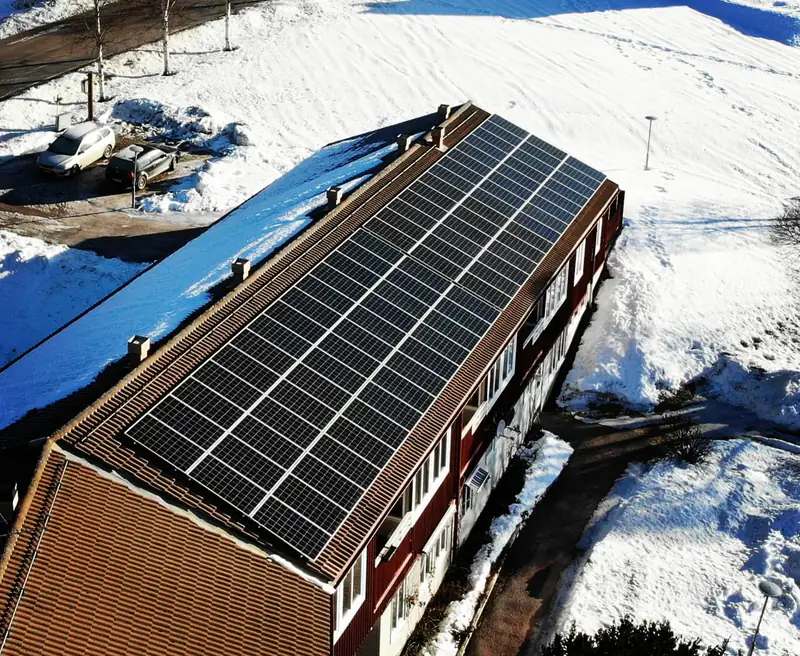Svågagården i Bjuråker — långt rött verksamhetshus med takmonterad solcellsanläggning i vintermiljö